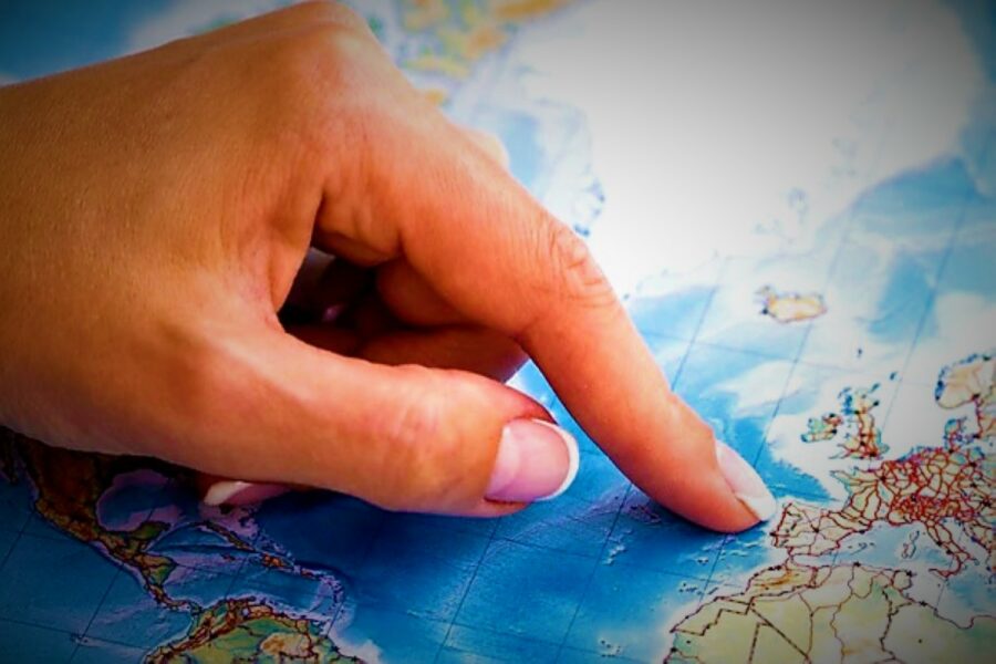 Un dedo de mujer señala la Península Ibérica en un mapamundi de fondo azul celeste