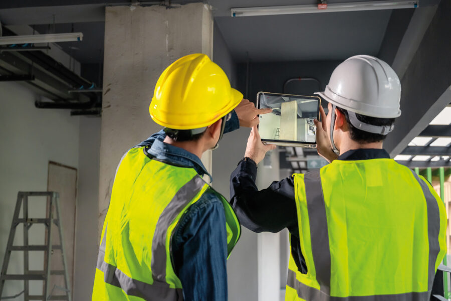 Dos trabajadores de el campo de la arquitectura con caso mirando una tablet