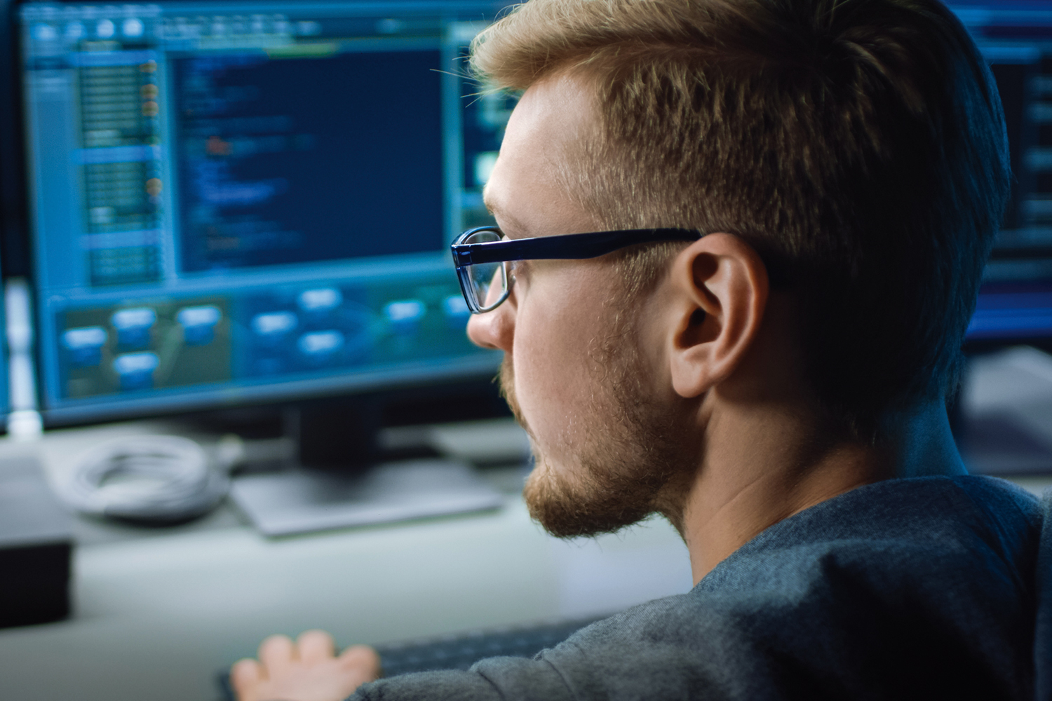 IT Specialist Works on Personal Computer with Screens Showing Software Program with Coding Language Interface. In the Background Technical Room of Data Center with Professional Working