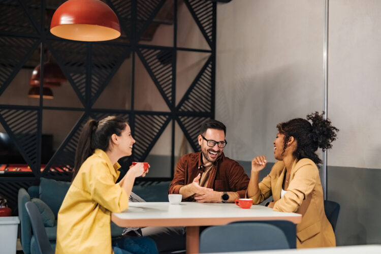 Cheerful business people talking on a work break, sitting and drinking coffee.